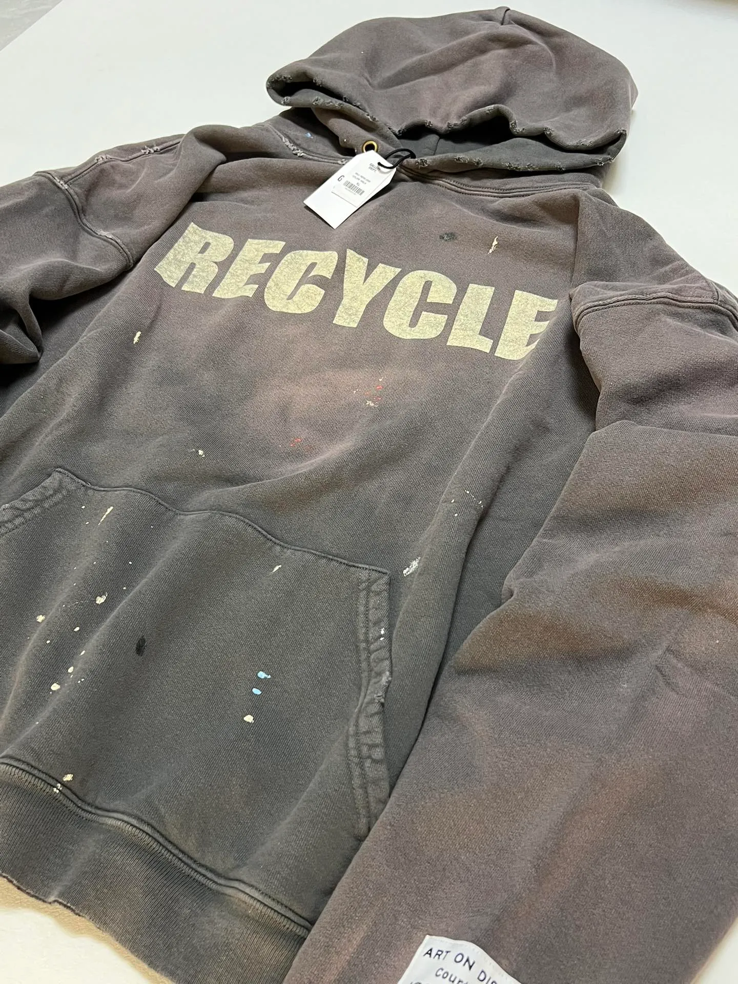 GALLERY DEPT. 90'S RECYCLE HOODIE WASHED BLACK 90'S washed hoodie with distressed eco-friendly slogans. Washed black S-XL. Ready-made garments are washed and dyed again. Multiple spots throughout the body are spray-faded. The ribs are cut and worn.